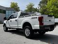 A white 2017 Ford F-250 Super Duty pickup truck with a flatbed and a distinctive ladder rack on the back