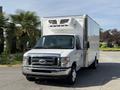A 2019 Ford Econoline box truck with a white exterior and a large refrigeration unit on top parked in a lot