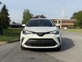 A white 2021 Toyota C-HR facing front with a distinctive grille and sharp headlights