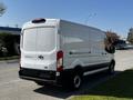 A white 2022 Ford Transit van with a high roof and rear doors positioned open showcasing a spacious cargo area