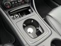 A center console compartment of a 2016 Mercedes-Benz GLA-250 with a circular cup holder and control knobs for climate and audio settings