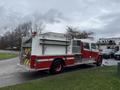 A red and white 2001 Freightliner FL80 fire truck with storage compartments on the side and a prominent rear pump panel