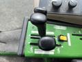 Close-up of the control levers on a 2014 John Deere 1585 Terrain Cut featuring a black joystick and various function buttons on a green panel