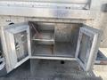 An open metal storage compartment on a 2007 Morgan Olson Workhorse W42 with two interior shelves and visible wiring inside