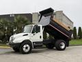 A 2006 International 4200 dump truck with a raised bed, displaying a white cab and black dump box