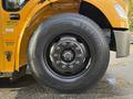 Close-up of the front wheel of a 2022 Freightliner B2 showing a black tire with deep treads and multiple lug nuts on a silver rim