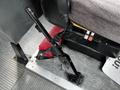 A large black lever attached to the floor inside a bus cabin positioned next to a seat with a red cushion visible in the foreground