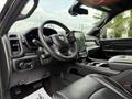 Interior view of a 2024 RAM 2500 featuring a black leather steering wheel digital display and central console with touchscreen controls