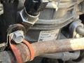 Close-up of a mechanical component from a 2022 Freightliner Cascadia featuring a labeled part with a metal connector and an orange rubber band securing a pipe