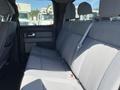 A 2014 Ford F-150 with a spacious gray cloth interior featuring a backseat with two head restraints and a seatbelt facing towards the front cabin