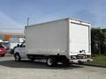 A 2023 Ford E-450 box truck with a white cargo area and a black bumper parked at an angle
