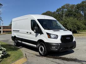 A white 2022 Ford Transit van with a black lower panel parked on a paved surface