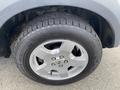Close-up of a silver alloy wheel with a black tire on a 2006 Land Rover LR3 showing detailed tread design and lug nut pattern