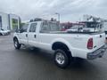 A white 2005 Ford F-350 SD truck with a flatbed and metal rack on the back parked in a lot
