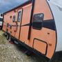 A 2015 Winnebago travel trailer in orange and black with a side entrance and windows visible