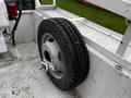 A spare tire mounted on a flatbed of a 2004 Ford F-450 SD with a silver rim and textured tread pattern