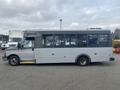 A 2016 Chevrolet Express mid-size bus with a gray exterior and large windows on the side