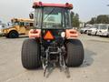 A 2010 Kubota M6040 tractor viewed from the rear showing large rear tires a three-point hitch and an orange triangular safety sign