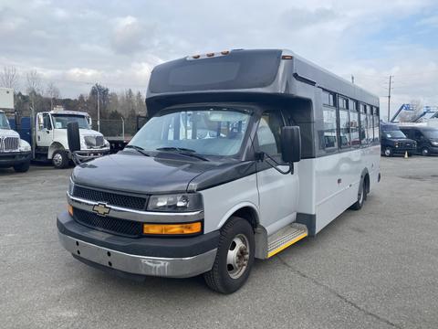 A 2016 Chevrolet Express bus with a black front, large windows, and a step entry, designed for passenger transport