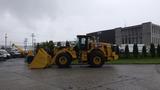 A 2019 Caterpillar 972M XE wheel loader with a yellow body and a large front bucket is parked on a concrete surface