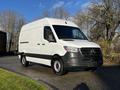 A 2021 Mercedes-Benz Sprinter van with a white exterior and black accents parked on a paved surface