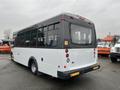 A 2018 Chevrolet Express passenger bus with a white body and gray accents seen from the rear showing its taillights and large windows