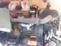 A close-up view of the engine compartment of a 2008 JLG Boom Lift showing complex machinery including pipes, valves, and various engine components