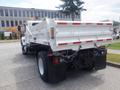 A 2012 International 7300 dump truck with a white cargo bed and red reflective stripes on the rear