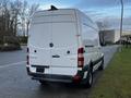 A white 2017 Mercedes-Benz Sprinter van parked on the street with a high roof and rear doors slightly ajar