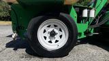 A close-up of a white-wheeled tire on a green 2017 Laymor SweepMaster 300 street sweeper