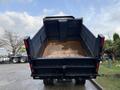 A 2015 Isuzu NPR HD truck with an open dump bed showing a stained floor and slight dirt present inside the bed