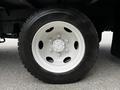 Close-up of a white wheel and tire from a 2018 Isuzu NPR truck showing multiple holes in the wheel rim for lug nuts and a textured tire tread