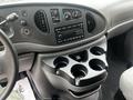 The interior of a 2008 Ford Econoline with a dashboard featuring controls for climate and audio along with a cup holder console