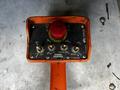 A handheld control panel with labeled buttons for rot, lift, extend, and winch functions, featuring an orange handle and a red emergency stop button