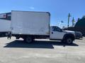 A 2015 Ford F-450 SD with a large white cargo box is parked in a lot with other vehicles around it