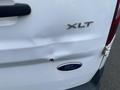 A white 2017 Ford Transit Connect with a dent on the rear door and the XLT model badge displayed above the Ford logo