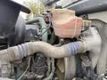 Close-up of the engine compartment of a 2012 Volvo VNL showing various components including a cooling reservoir hose and metal pipes