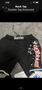Black MMA shorts with the word "Warrior" prominently displayed on the waistband and various designs on the sides including logos and graphics