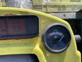 Close-up of the fuel gauge on a yellow dashboard showing the fuel level near empty with warning lights above the gauge