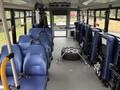 Interior of a 2020 Chevrolet Express with blue seats arranged in rows and a mounted spare tire in the center aisle