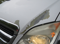 A 2009 Dodge Sprinter Van with a damaged hood showing peeling paint and a visible headlight