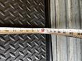 A measuring tape is laid across a textured surface, with markings indicating various measurements up to 100 inches