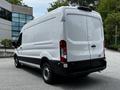 A 2022 Ford Transit van with a white exterior and a black bottom section is shown from the rear angle, featuring a high roof and large cargo area