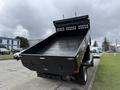 A 2021 Ford F600 dump truck with a raised bed displaying its interior features a smooth black surface and a tarp cover at the rear