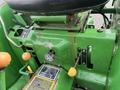 The control panel of a 2003 John Deere 790 featuring levers switches and gauges in green and yellow colors with a seat above