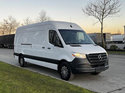 A white 2019 Mercedes-Benz Sprinter van parked with a high roof and black accents on the sides and front