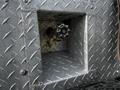 A metal compartment with a diamond plate pattern features a brass valve with a star-shaped handle inside