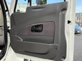 A door panel of a 2011 International WorkStar featuring a textured brown insert and a handle for opening the door