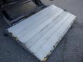 A metal loading ramp with a textured surface and yellow safety stripes along the edge