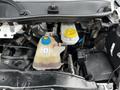 Close-up of the engine compartment of a 2021 RAM Promaster showing the coolant reservoir with a yellow cap and a clear container displaying coolant levels